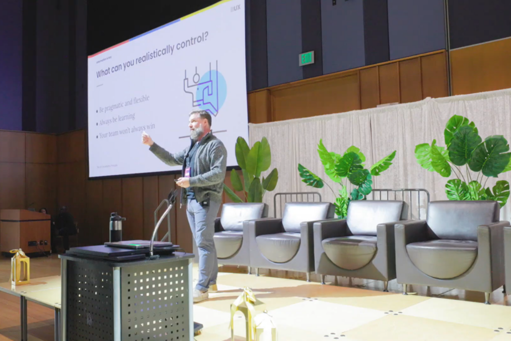 Speaker presenting UX insights on stage at UXCON 2025