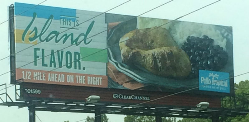 A billboard uses a decorative font that makes the slogan 'This is Island flavor' appear to say 'This is bland flavor.'