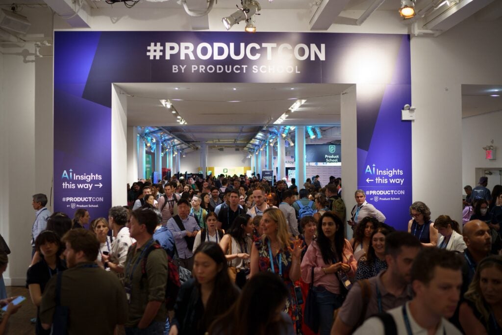 Una gran multitud de asistentes se reúne en un concurrido salón de conferencias en ProductCon organizado por Product School